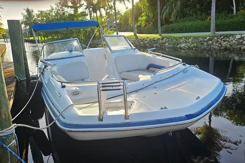 The Image of 2006 Hurricane SunDeck 237 OB boat docked by lush greenery and calm water. - 0