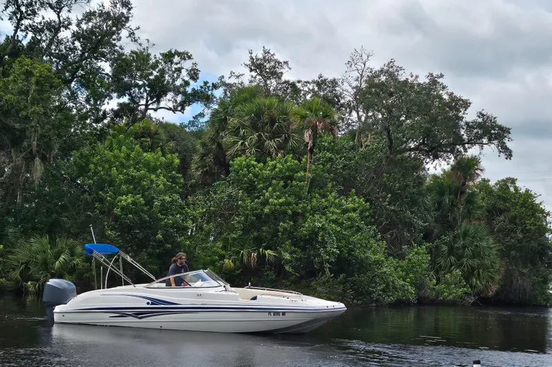 Slide: The Image of 2006 Hurricane SunDeck 237 OB boat cruising on a scenic river with lush greenery. - 23