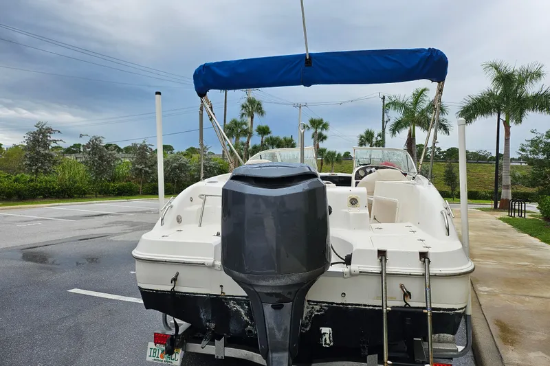Slide: The Image of 2006 Hurricane SunDeck 237 OB boat with blue canopy, parked near palm trees. - 4