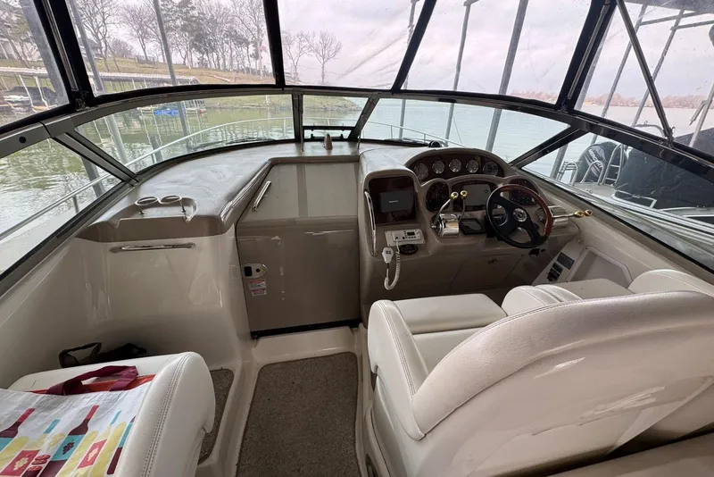 Slide: The Image of 2005 Sea Ray 340 Sundancer helm with steering wheel, gauges, and controls, docked by the water. - 14