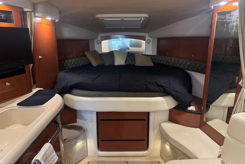 Slide: The Image of 2005 Sea Ray 340 Sundancer cabin interior with bed, TV, and wooden cabinetry. - 25