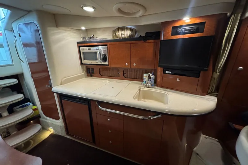 Slide: The Image of 2005 Sea Ray 340 Sundancer interior kitchen with microwave, sink, and TV. - 27