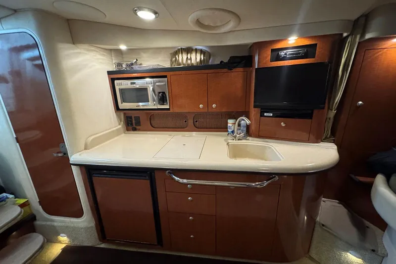 Slide: The Image of 2005 Sea Ray 340 Sundancer yacht interior kitchen with microwave, sink, and cabinets. - 28