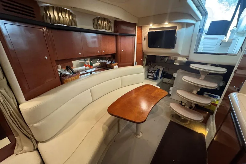 Slide: The Image of Interior of 2005 Sea Ray 340 Sundancer with curved seating and wooden table. - 29