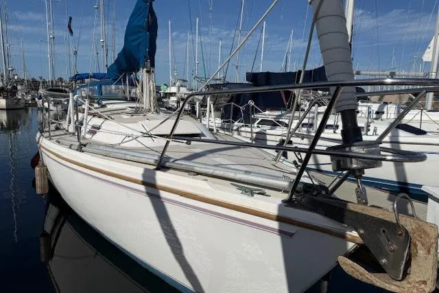Slide: The Image of 1986 Catalina 36 sailboat docked in a marina, featuring a sleek white hull and blue sail. - 1