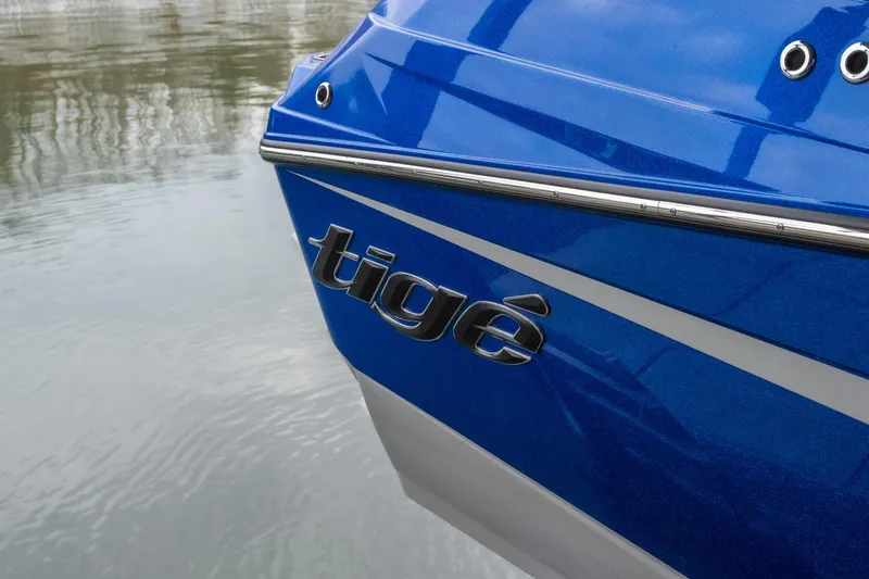 Slide: The Image of 2026 Tigé Z3 boat, blue hull with logo, reflecting on calm water. - 2