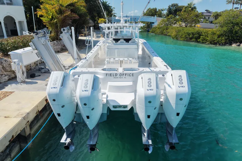 Slide: The Image of 2023 Invincible 46 Catamaran with quad 400 V10 engines docked in turquoise water. - 12