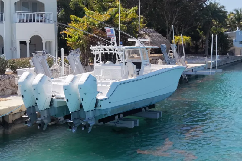 Slide: The Image of 2023 Invincible 46 Catamaran docked, featuring multiple outboard engines, in a tropical setting. - 4