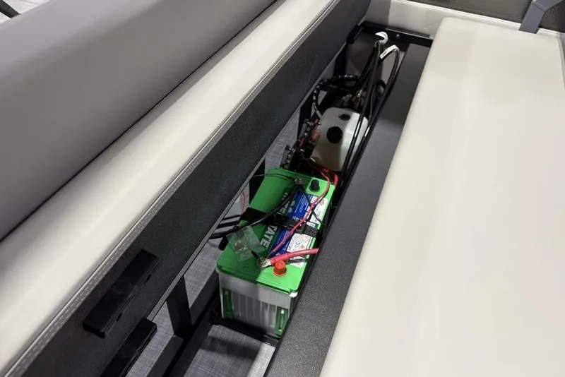 Slide: The Image of Battery compartment of 2026 Premier 220 Sunscape RL - CL boat, featuring a green battery. - 24
