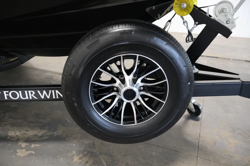 Slide: The Image of 2026 Four Winns HD2 OB trailer wheel with black alloy rim in a garage setting. - 48