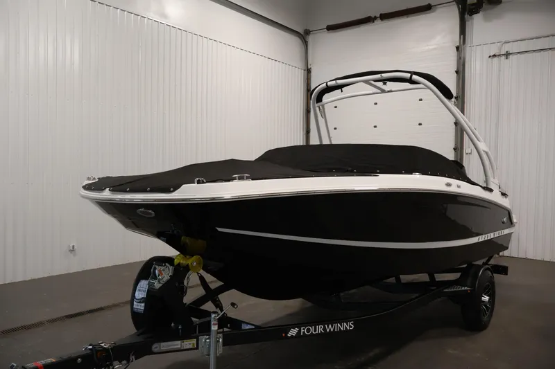 Slide: The Image of 2026 Four Winns HD2 OB boat in showroom, black hull, covered, on trailer. - 51