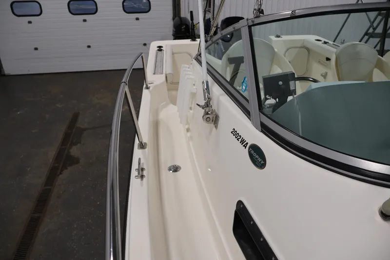Slide: The Image of 2004 Trophy 2002 Walkaround boat interior with white seats and windshield in a garage setting. - 15