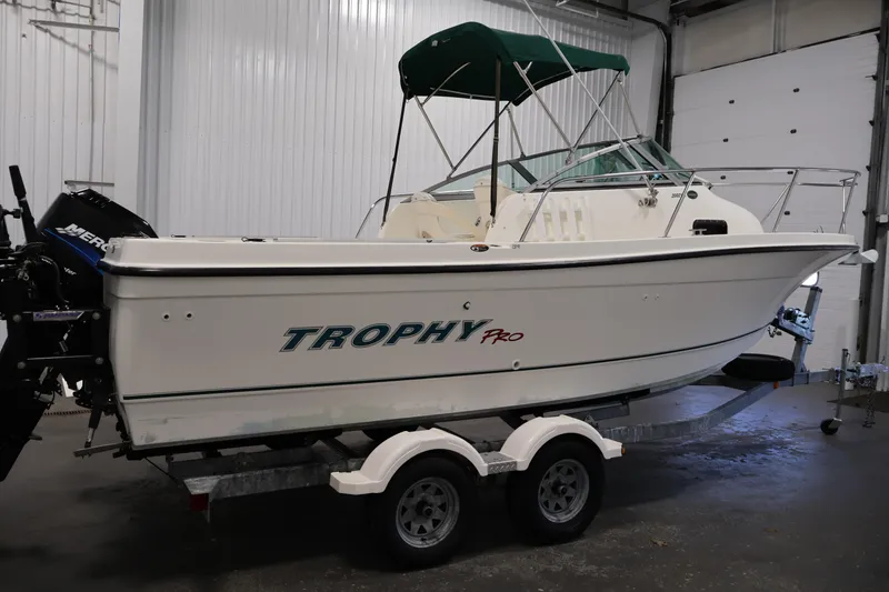 Slide: The Image of 2004 Trophy 2002 Walkaround boat with green canopy on trailer in garage. - 3