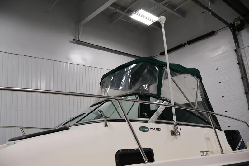 Slide: The Image of 2004 Trophy 2002 Walkaround boat in indoor storage, featuring green canopy and railing. - 64