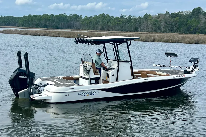 Slide: The Image of 2021 Caymas 26 HB boat on a calm lake with a scenic forest backdrop. - 2
