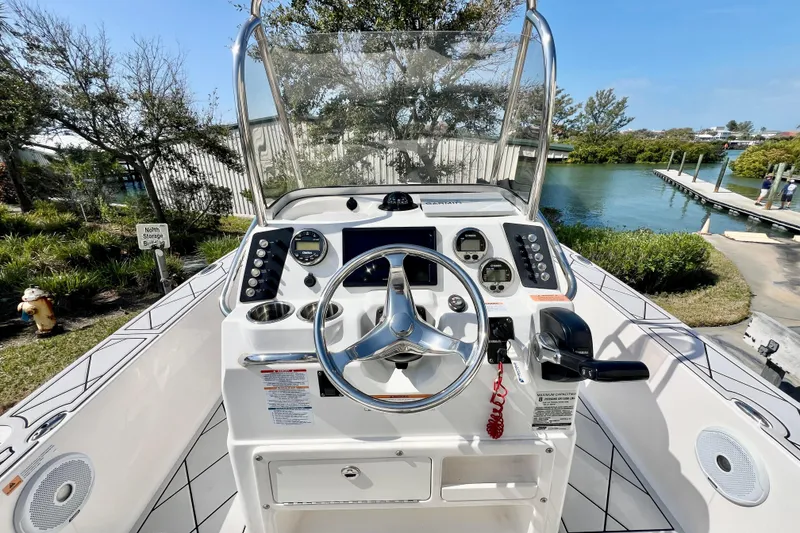 Slide: The Image of 2019 Robalo 206 Cayman boat console with steering wheel and controls, dockside view. - 2