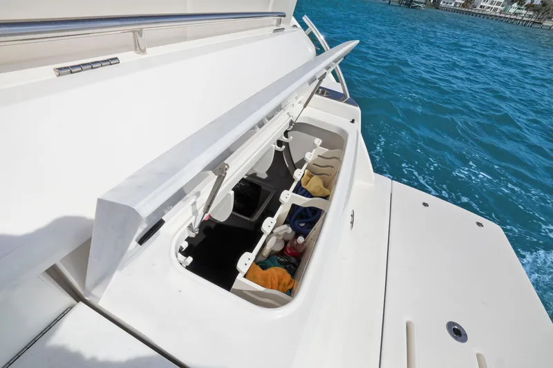 Slide: The Image of 2023 Tiara Yachts C49 Coupe storage compartment open on deck, near blue ocean water. - 18