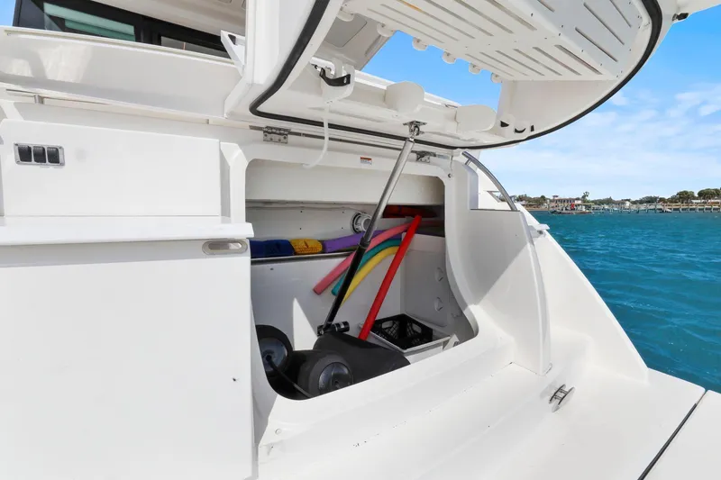 Slide: The Image of 2023 Tiara Yachts C49 Coupe storage compartment with pool noodles, docked by blue water. - 19