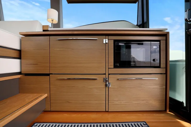Slide: The Image of 2023 Tiara Yachts C49 Coupe interior with wooden cabinetry and built-in microwave. - 44