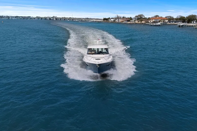 Slide: The Image of 2023 Tiara Yachts C49 Coupe cruising on open water, scenic coastal backdrop. - 78