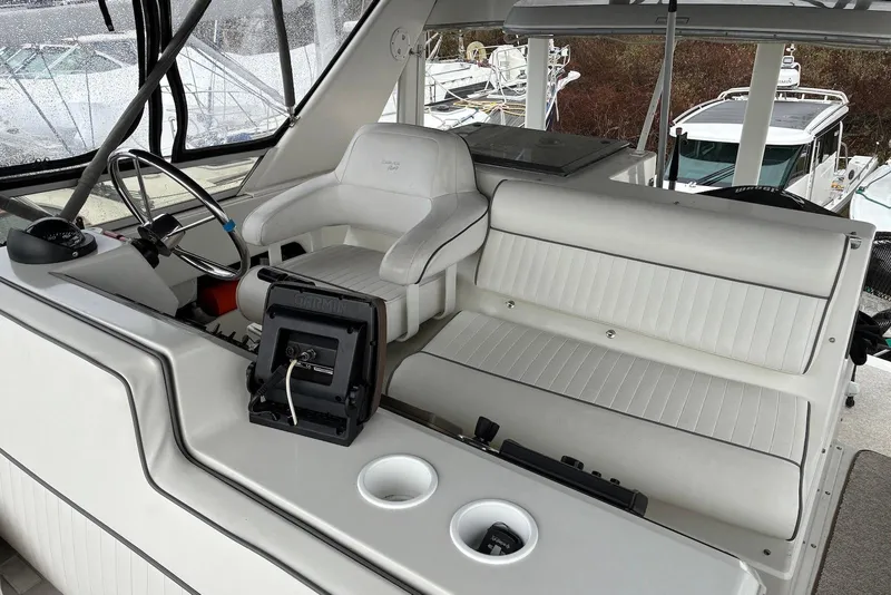 Slide: The Image of 1994 Carver 370 Aft Cabin Motor Yacht helm with white seating and navigation equipment. - 2