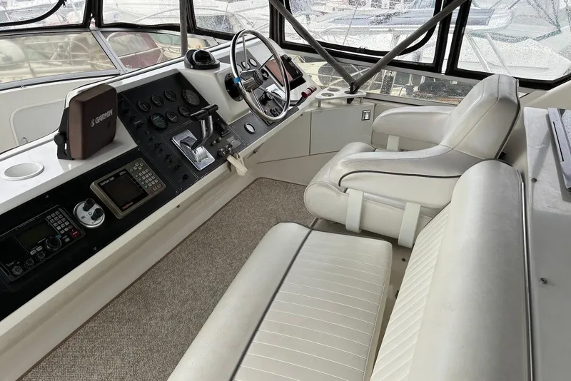 Slide: The Image of 1994 Carver 370 Aft Cabin Motor Yacht helm with white seating and navigation equipment. - 3