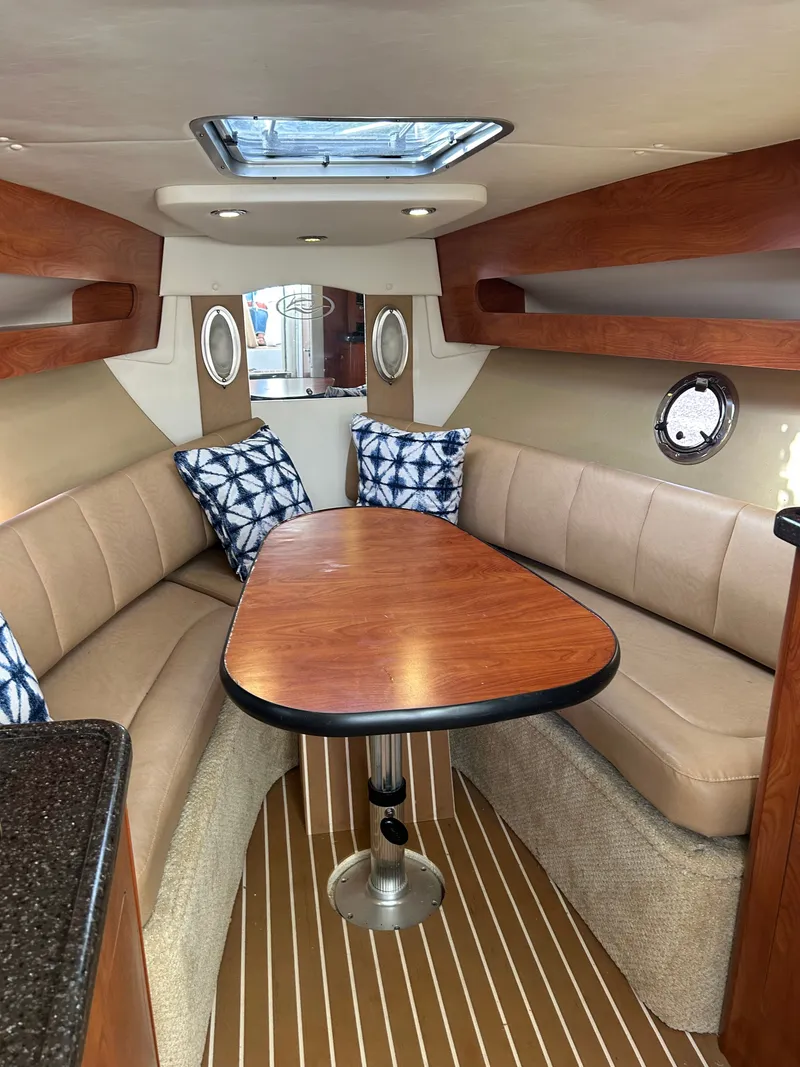 Slide: The Image of Interior of 2013 Rinker 290 Express Cruiser with wood table and cushioned seating. - 21