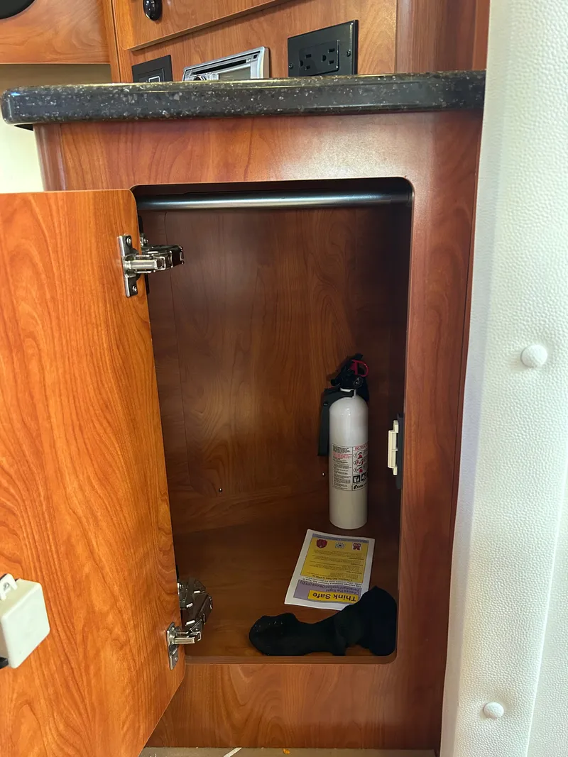 Slide: The Image of Open cabinet in 2013 Rinker 290 Express Cruiser with fire extinguisher. - 48