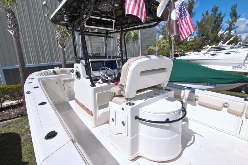 Slide: The Image of 2018 Sea Chaser 27 HFC boat interior with seating and console, docked outdoors. - 17