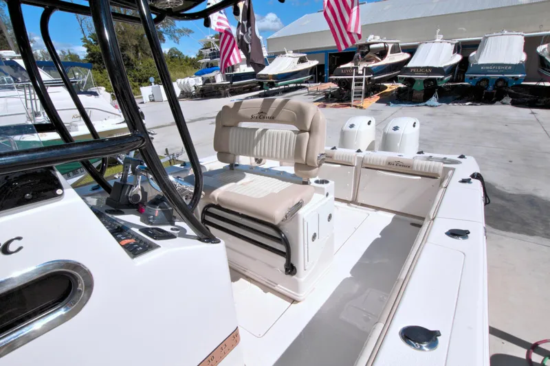 Slide: The Image of 2018 Sea Chaser 27 HFC boat interior with seating and control panel, docked near other boats. - 18
