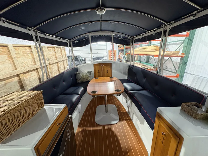 Slide: The Image of Interior of a 2021 Duffy Cuddy Cabin with wooden table and blue seating. - 24