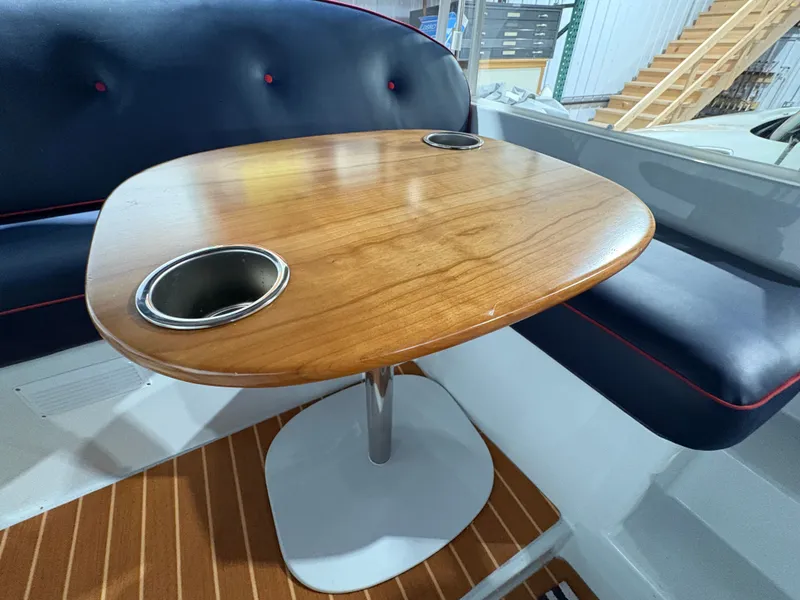 Slide: The Image of Interior of a 2021 Duffy Cuddy Cabin with wooden table and blue cushioned seating. - 28