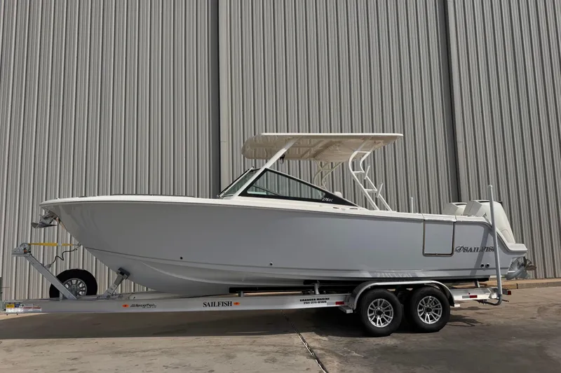 Slide: The Image of 2026 Sailfish 276 DC boat on trailer, parked near a corrugated metal wall. - 1