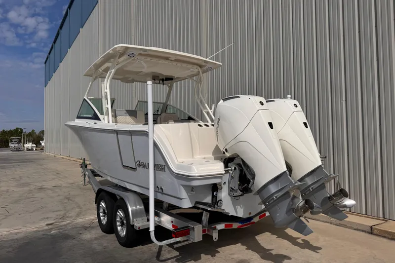 Slide: The Image of 2026 Sailfish 276 DC boat with dual engines on a trailer, parked near a large building. - 3