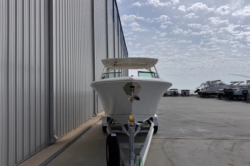 Slide: The Image of 2026 Sailfish 276 DC boat on trailer beside a metal building under a cloudy sky. - 7