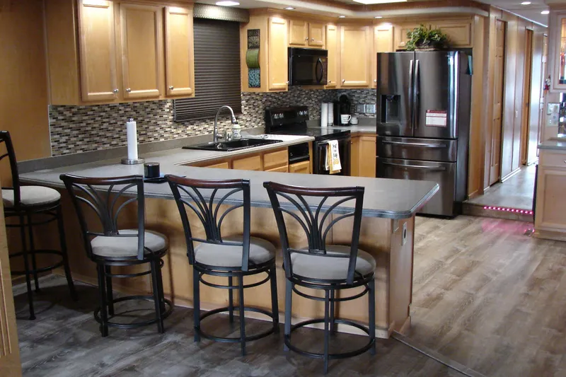 Slide: The Image of Modern kitchen interior in a 1999 Sumerset 18x90 houseboat with bar stools and stainless steel appliances. - 10
