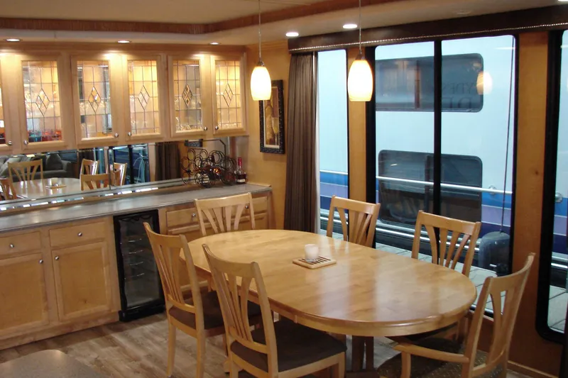 Slide: The Image of Elegant dining area in a 1999 Sumerset 18x90 houseboat with wooden furniture and glass cabinets. - 14
