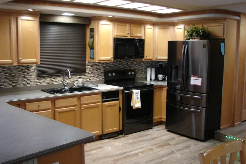 Slide: The Image of Modern kitchen in a 1999 Sumerset 18x90 houseboat with stainless steel appliances and wooden cabinetry. - 16
