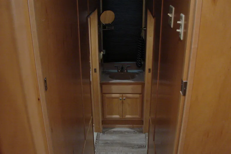 Slide: The Image of Narrow hallway with wooden cabinets leading to a small sink area in a 1999 Sumerset 18x90. - 20