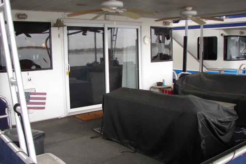 Slide: The Image of 1999 Sumerset 18x90 houseboat deck with covered furniture and American flag decor. - 3