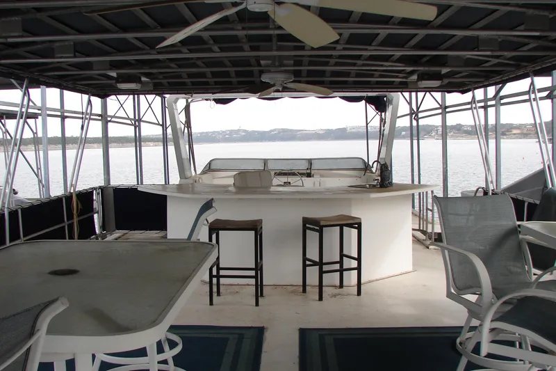Slide: The Image of 1999 Sumerset 18x90 houseboat interior with bar, stools, and lake view. - 6