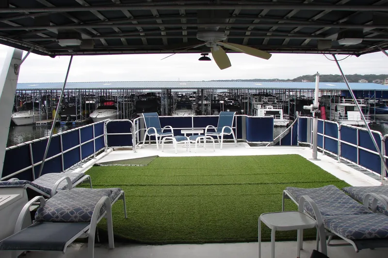 Slide: The Image of 1999 Sumerset 18x90 houseboat deck with seating, artificial grass, and marina view. - 7
