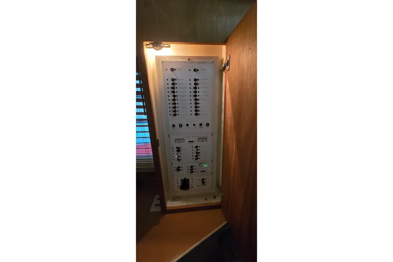 Slide: The Image of Electrical panel inside a 1998 Silverton 322 Motor Yacht, illuminated and enclosed in a wooden cabinet. - 39