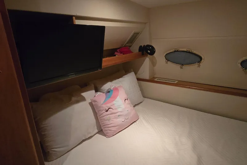 Slide: The Image of 1998 Silverton 322 Motor Yacht cabin with bed, TV, and decorative pillow. - 44