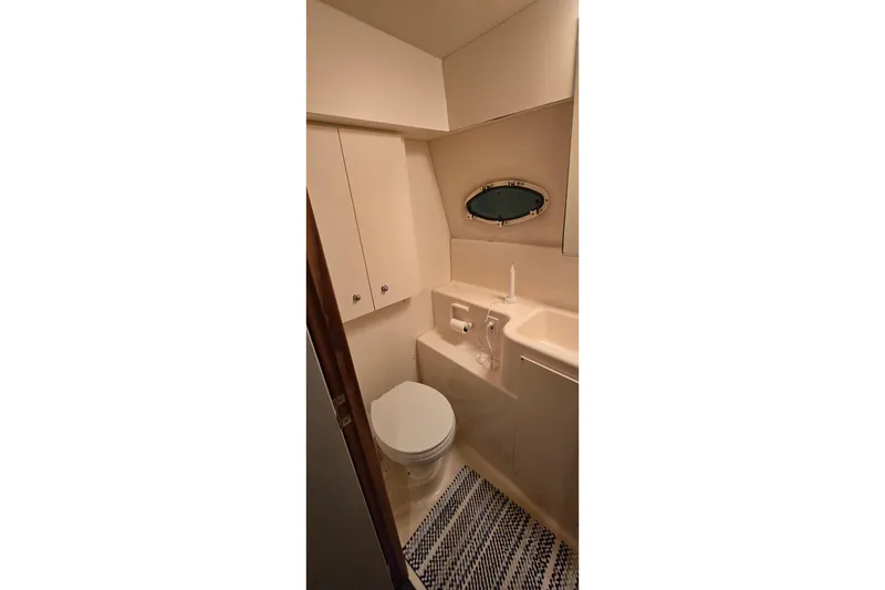Slide: The Image of 1998 Silverton 322 Motor Yacht bathroom with toilet, sink, and oval window. - 46