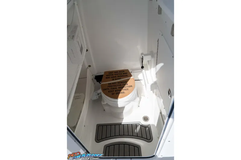 Slide: The Image of Interior of 2026 Sea Hunt Ultra 265 SE boat, featuring a compact marine toilet. - 27