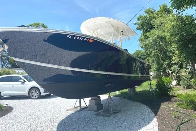 Slide: The Image of 2015 Regulator 28 Forward Seating boat on stands, parked on gravel driveway. - 10