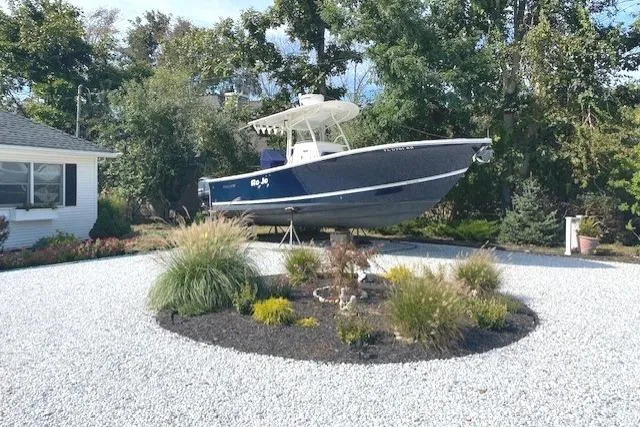 Slide: The Image of 2015 Regulator 28 Forward Seating boat displayed in a landscaped yard with trees. - 11