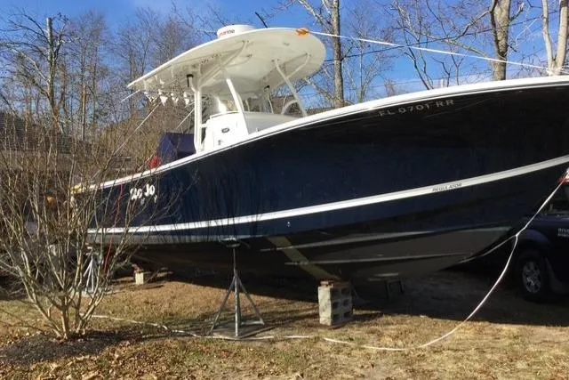 Slide: The Image of 2015 Regulator 28 Forward Seating boat on stands, outdoors, with trees in the background. - 13