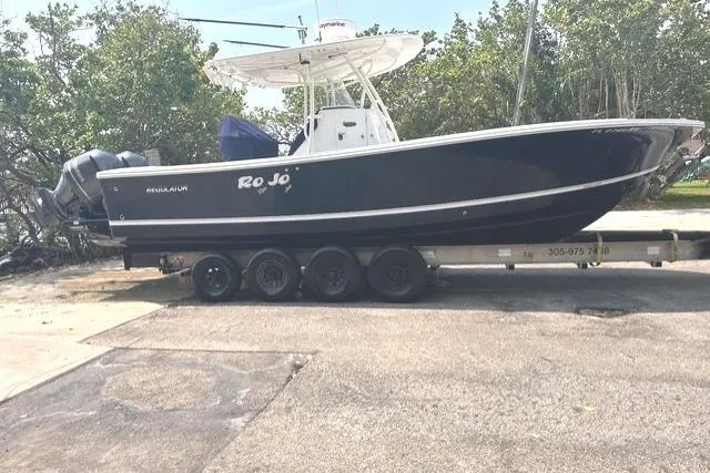 Slide: The Image of 2015 Regulator 28 Forward Seating boat on trailer, parked outdoors. - 14